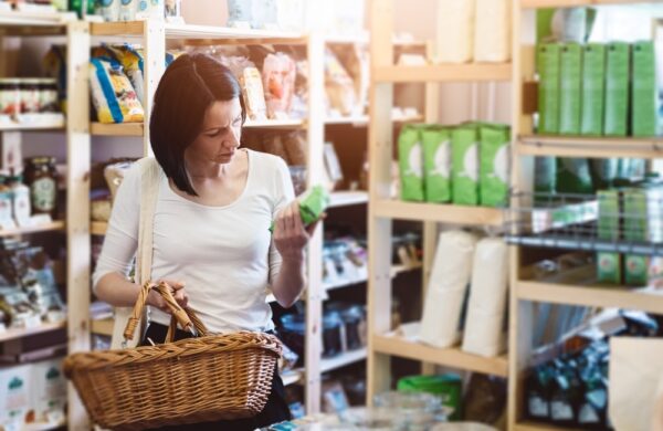 vrouw die in een winkel staat bekijkt achterkant van een verpakking