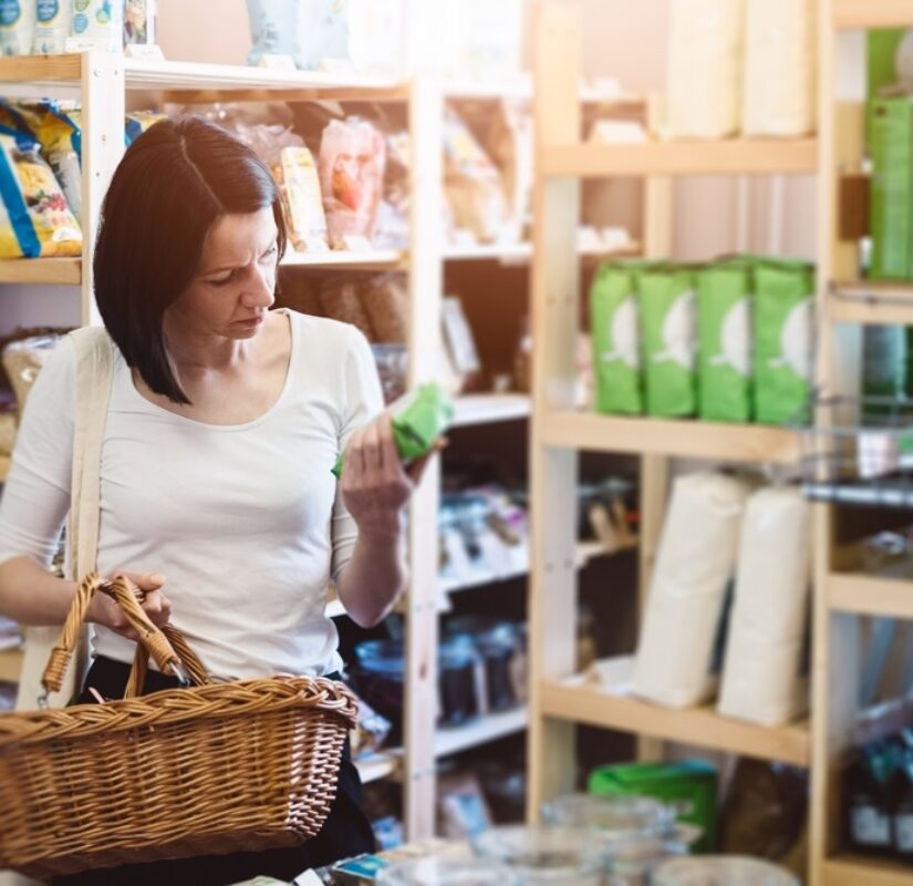 vrouw die in een winkel staat bekijkt achterkant van een verpakking